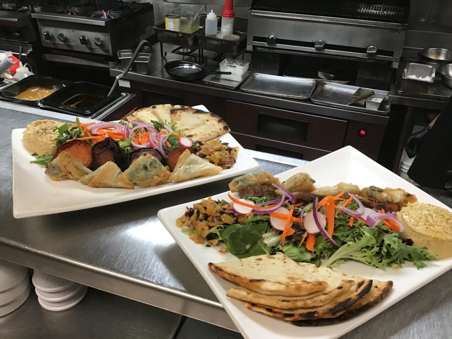 Two platters of flatbread and salad dishes