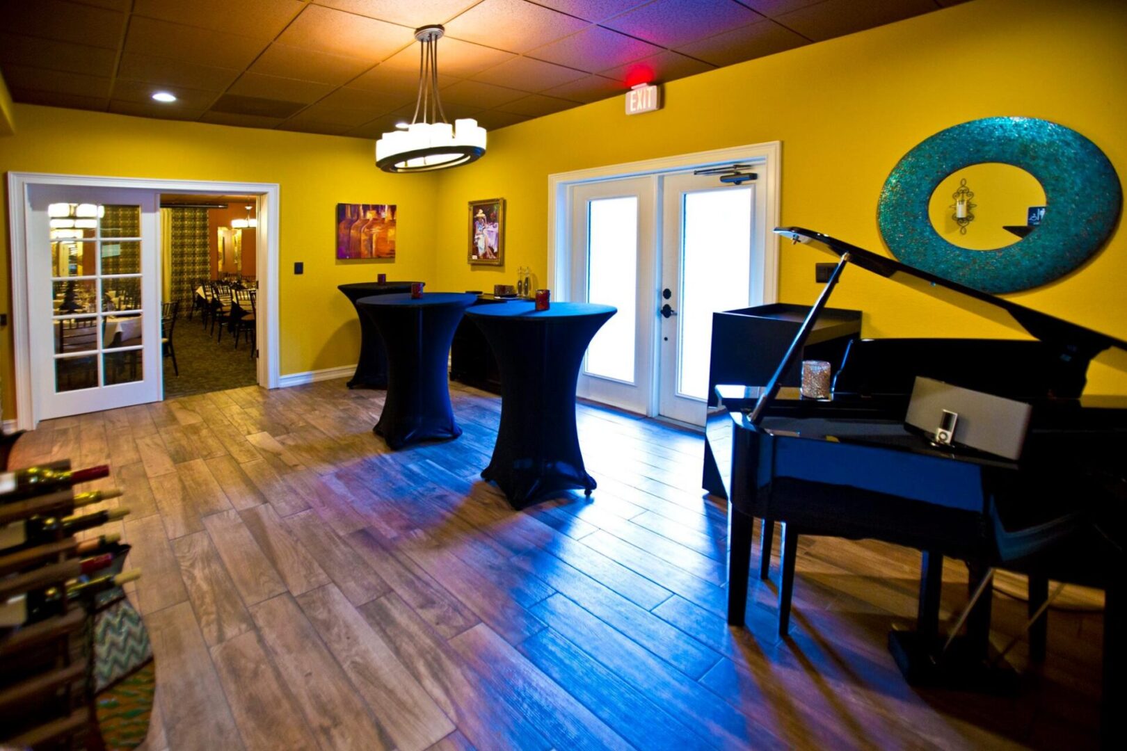 Yellow waiting room with three cocktail tables and a grand piano