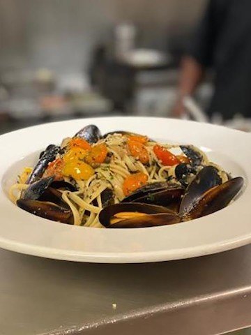 White plate of white pasta with mussels