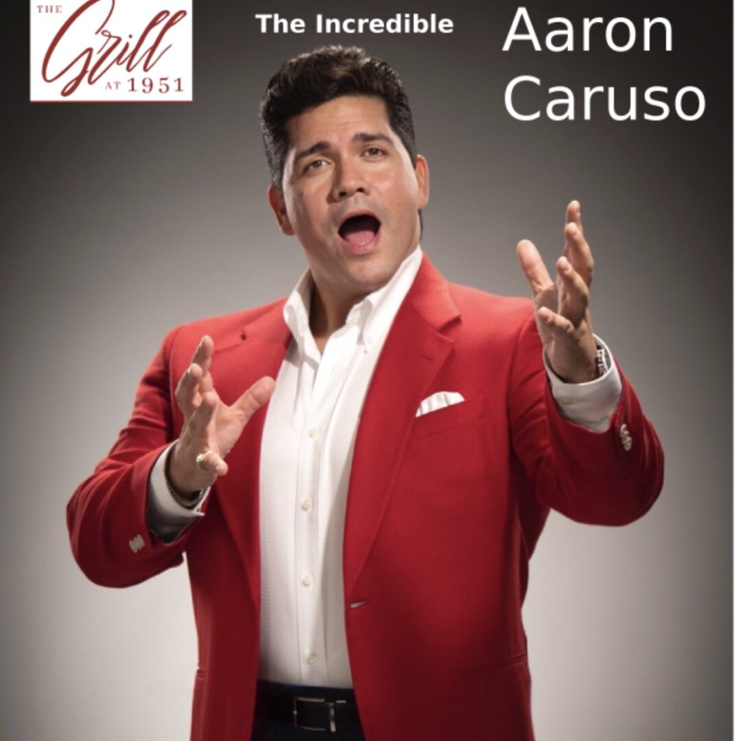 Aaron Caruso belting out a song while wearing a red suit jacket