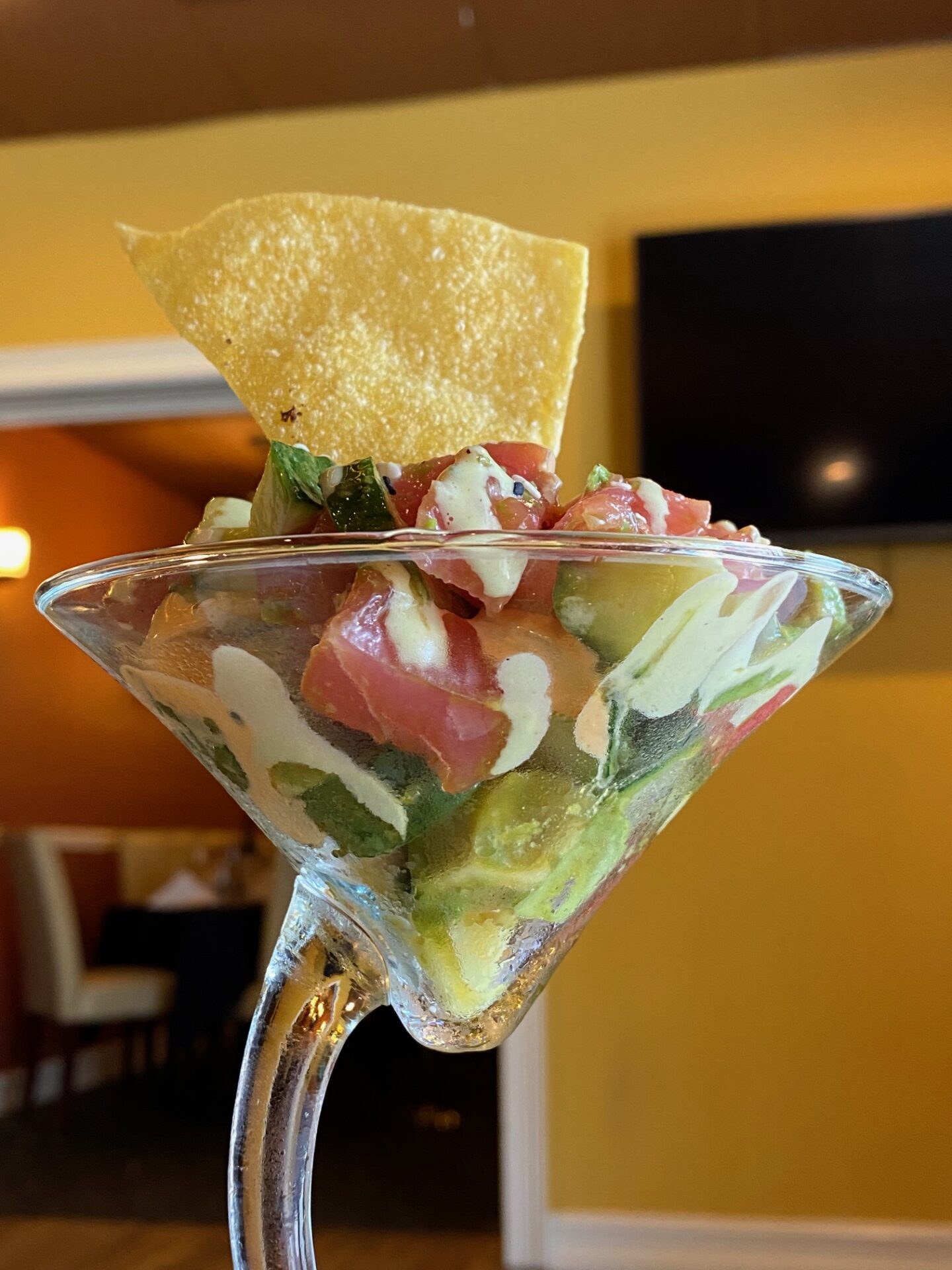 Tortilla chip standing upright on top of fresh salsa placed in a cocktail glass with a curved handle