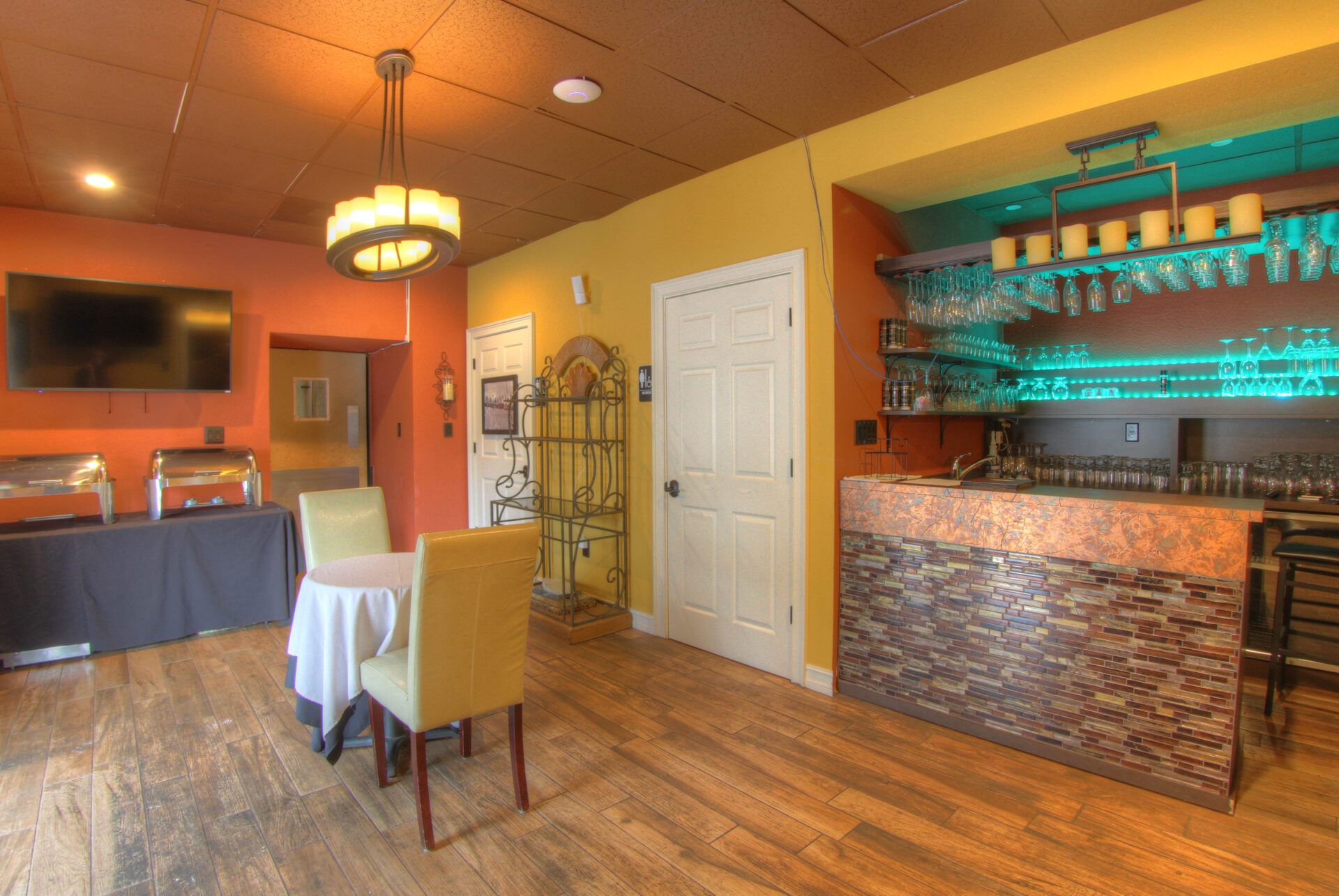 Bricked bar area overlooking a two-person table in a yellow and orange-painted room