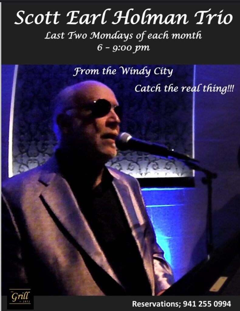 A man in sunglasses and black jacket singing.